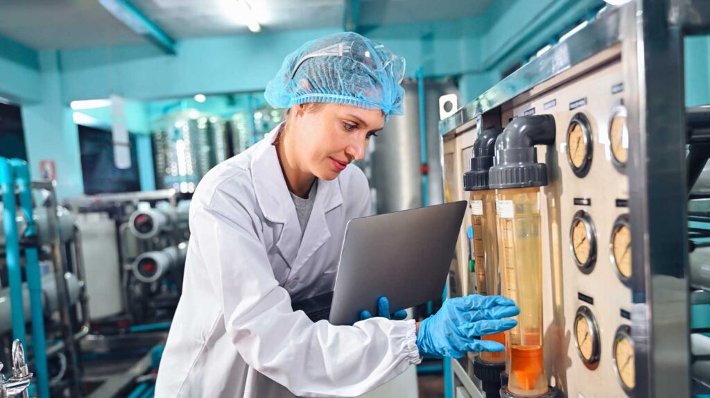 Female engineer inspecting water filtration equipment in a facility.